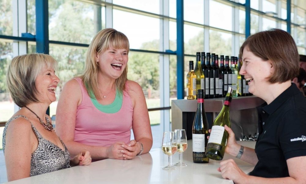 three woman laugh as they taste wine