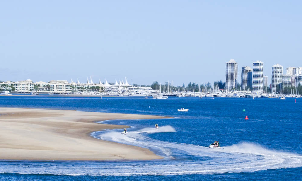 jet skis cruising along side of sand bank